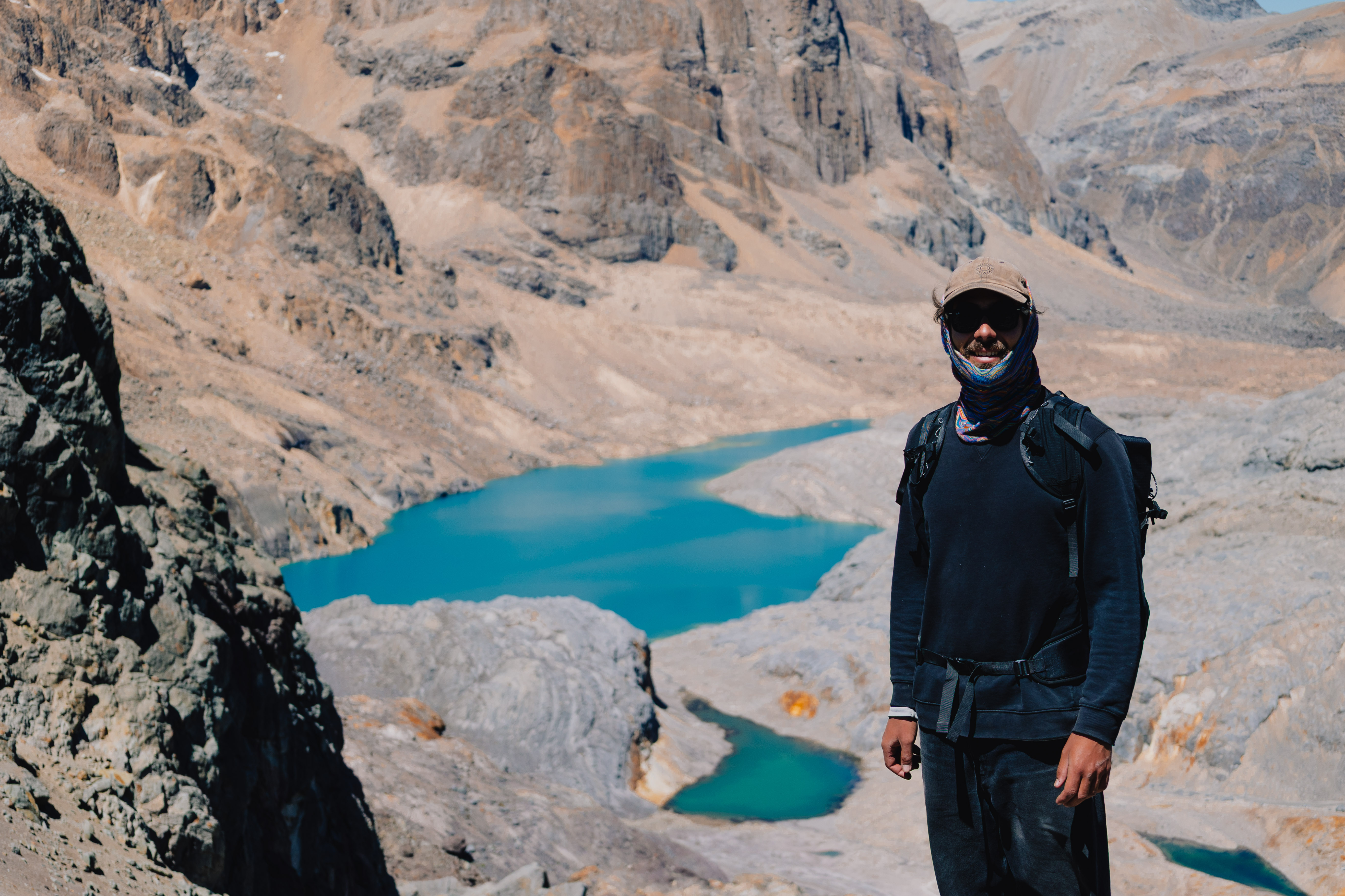 Huayhuash – Luca eingemummt mit Buff vor einem türkisen Bergsee