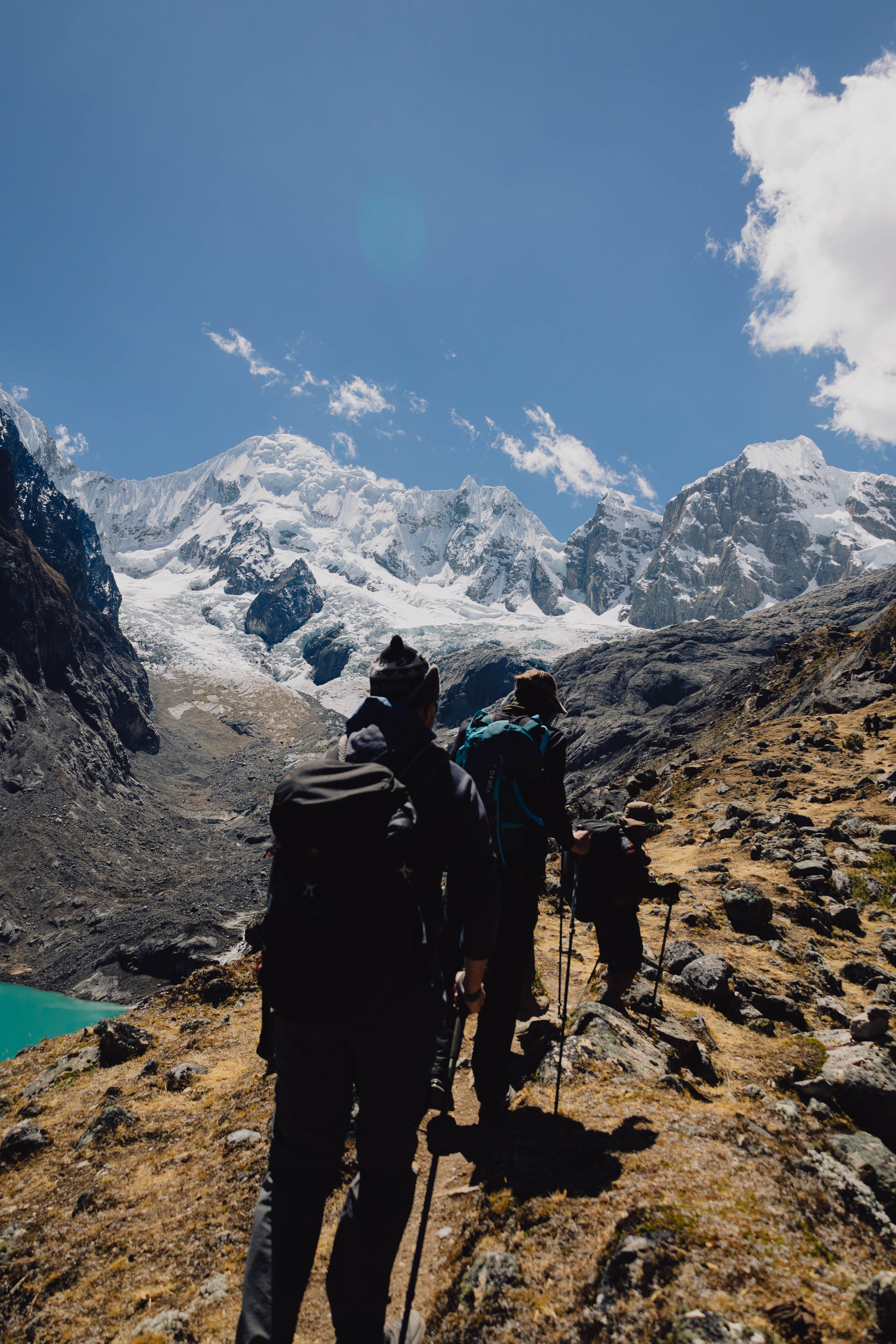 Huayhuash – zwei Silhouetten auf einem Pass mit Weitsicht auf Gipfel und See