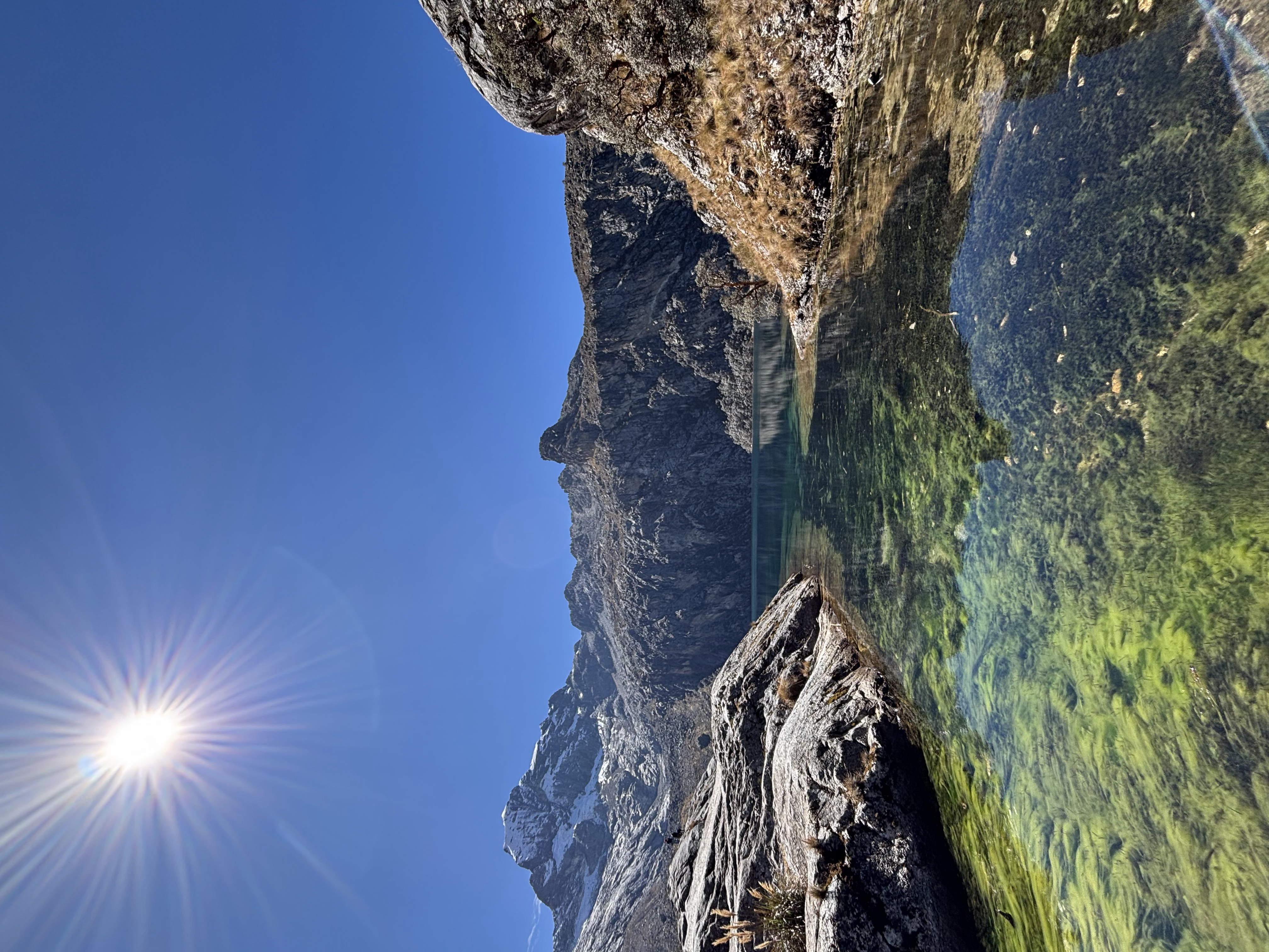 Huayhuash – Sonnenstern über einem Berg, gespiegelt in einem klaren Bergsee
